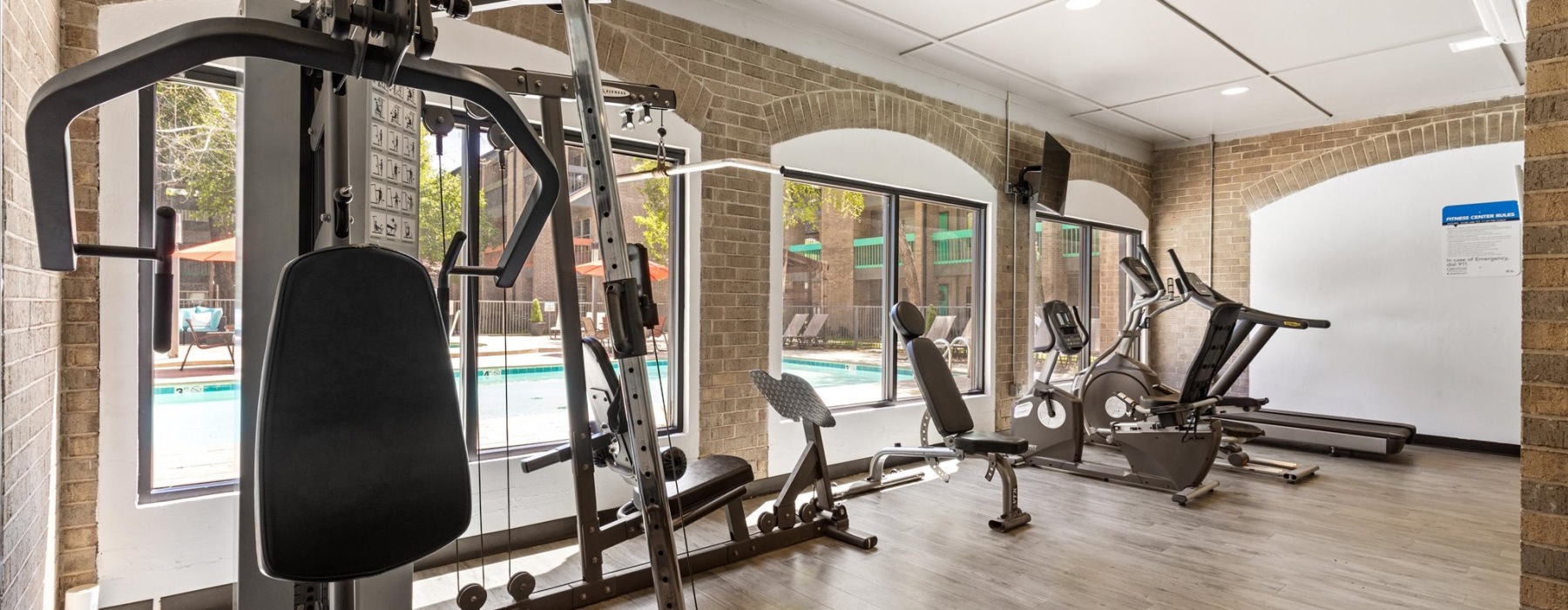Fitness center with machines and large windows with pool right outside at The Haven apartments in OKC, OK.